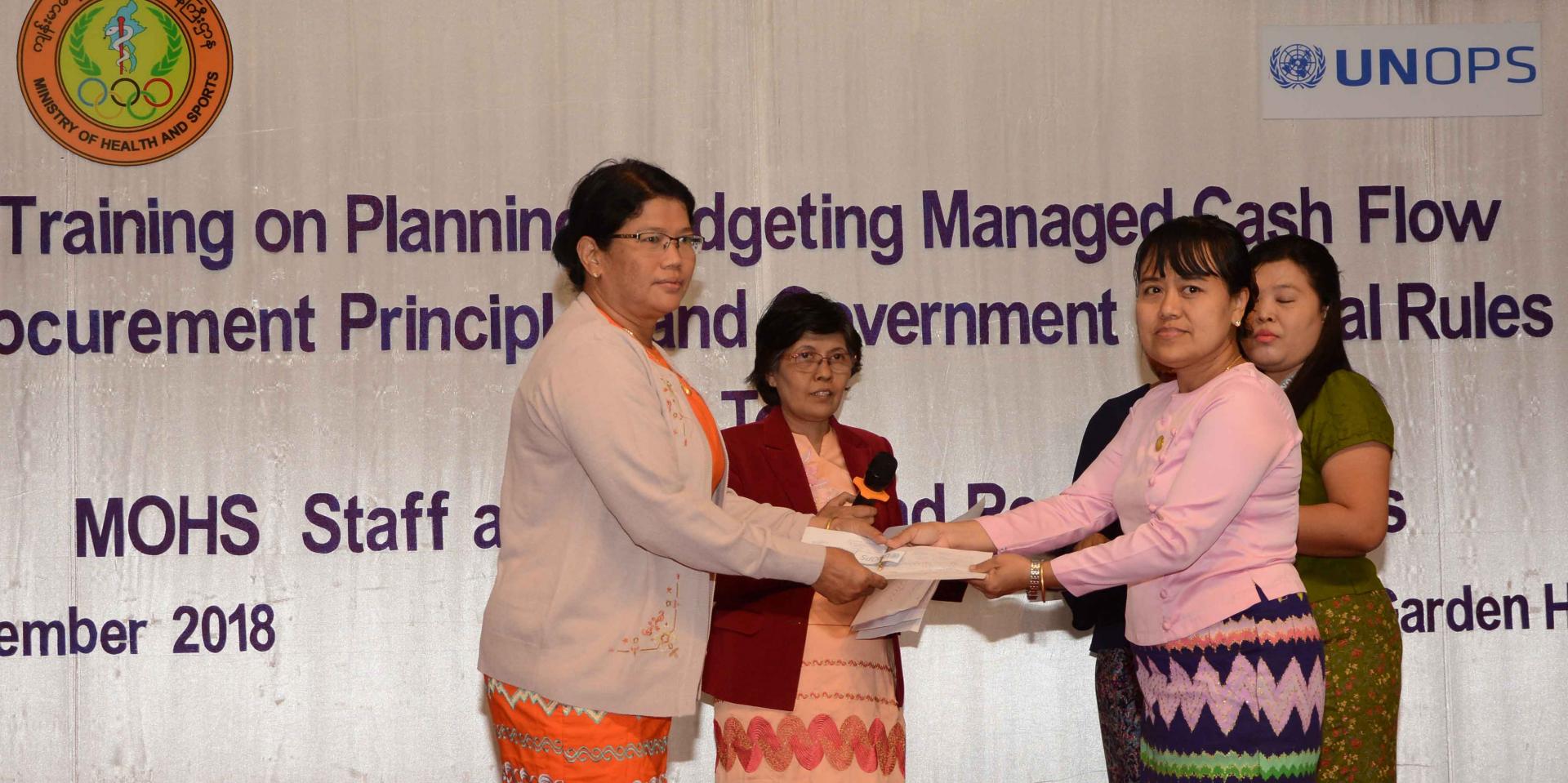 MOHS Yangon Region North District Health Department Deputy Director Dr Khin Sandar Aung presents prizes to participants who scored high marks in the practical workplanning exercises. Photo: UNOPS