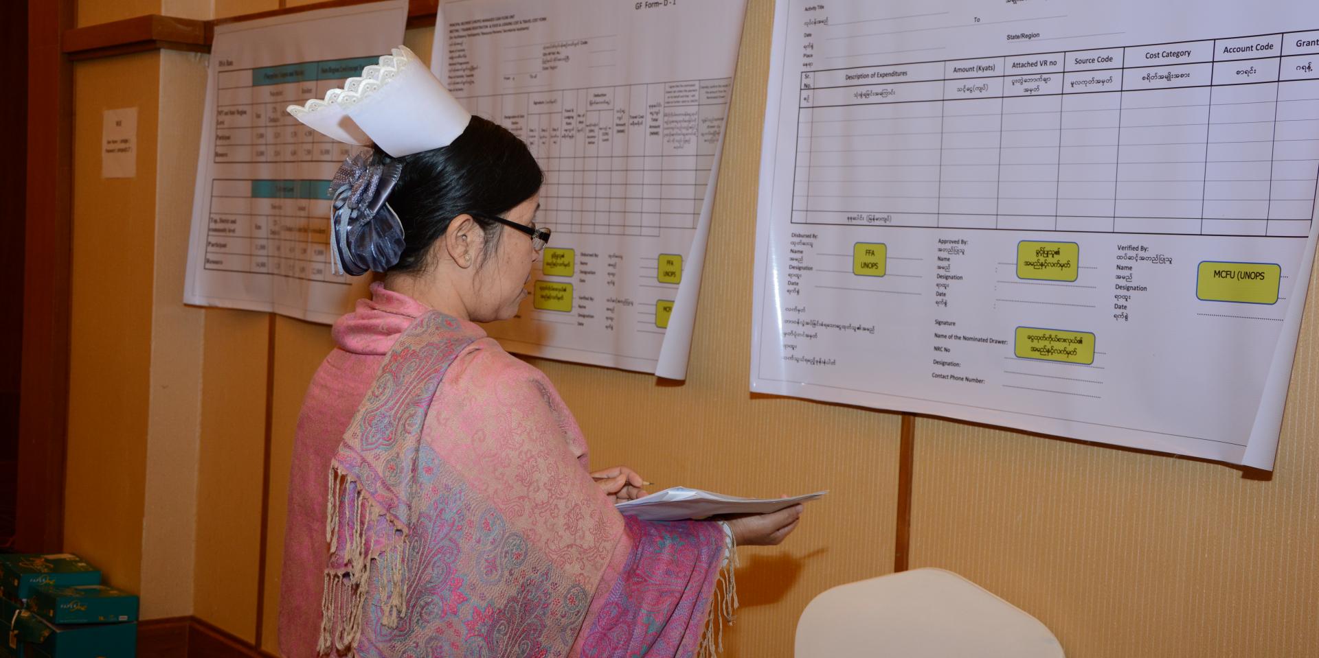 During the group-work practice of the financial management training, Managed Cash Flow forms and formats were displayed in the training room. This helped familiarize health staff participants with the forms and their use. A Township Health Nurse (THN) carefully reads the forms and formats and takes notes. Nay Pyi Taw, 2017.