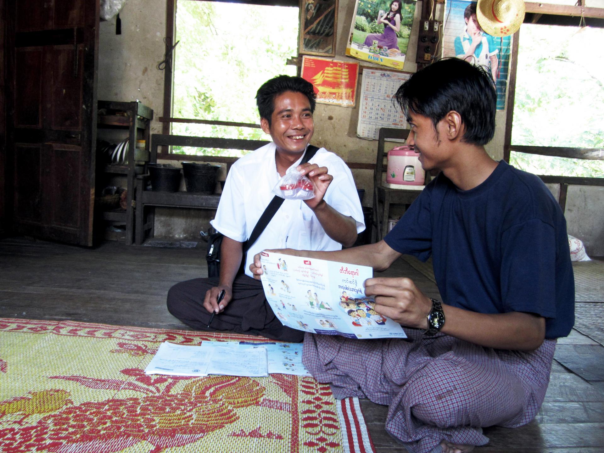 Ko Kyaw Kyaw Myint reassures Ko Han Min Htun who is about to have a month-2 sputum check- up for tuberculosis. Volunteers are always on hand to help patients once they have received their test results. Tharzi township, Mandalay Region. Photo: UNOPS