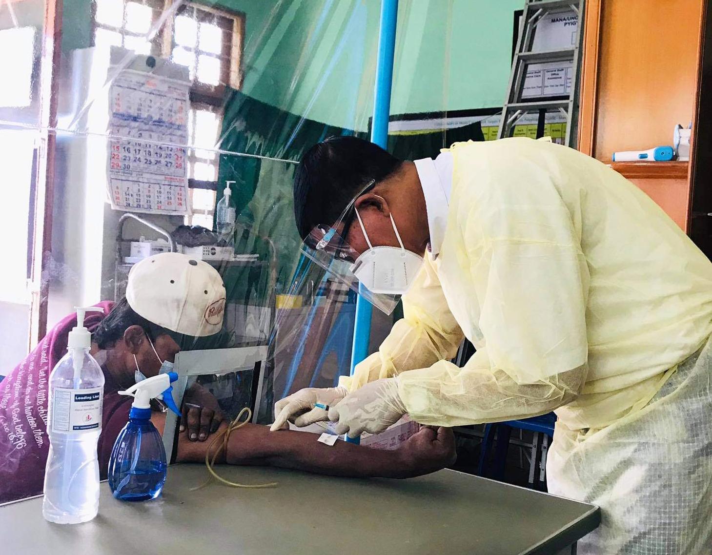 Peer educator Min Min Naing performing blood testing with protective measures at Pyigyitagon KSC. Photo: MANA